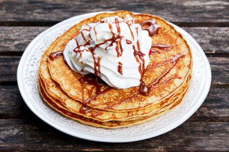 Fresh golden pancakes with cream and chocolate.の写真素材