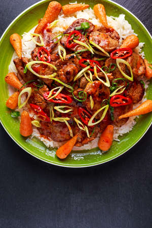 takeawy classic pork on rice with fried in sticky souce carrots, sprinkle of chillie and spring...