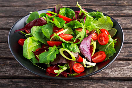 Baby leaves salad with cherry tomatoes and leek rings.の写真素材