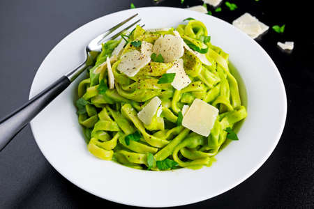 Tagliatelle pasta with spinach, avocado and parmigiano cheese, herbs in white plate. concept of...