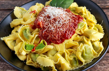 Traditional Italian homemade spinach and ricotta tortellini With marinara souce and parmesan.の写真素材