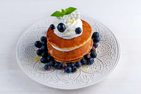 Pancakes with blueberries and cream on white plate.の写真素材
