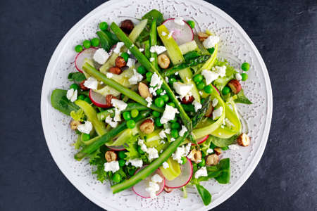Fresh Green Asparagus salad witch Goat Cheese, peas, radishe, zucchini, lettuce and Hazelnutsの写真素材