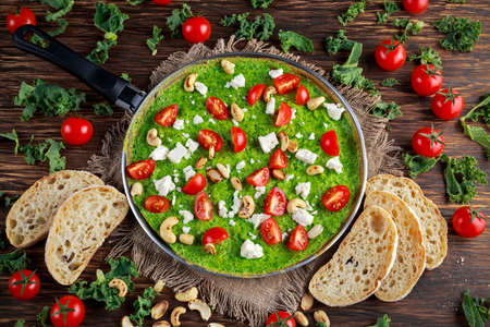 Vegetables Green Omelette with tomatoes, kale, greek cheese, olives, nuts, toast on wooden background. concept healthy food.の写真素材