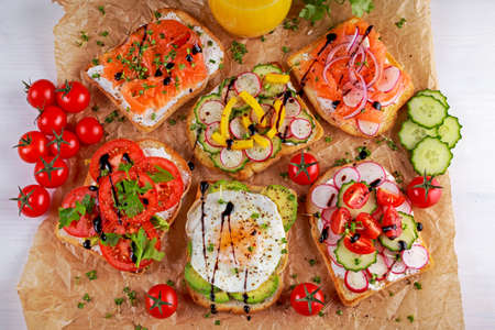 Variety of vegetarian toast sandwiches with salmon, raddish, tomatoes, cucumber, avocado,fried egg and sweet pepper.の写真素材