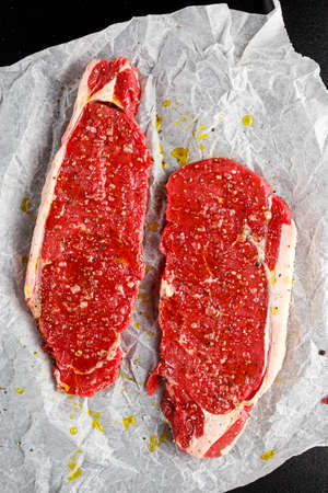 Raw seasoned sirloin prime british steaks on paper.の写真素材