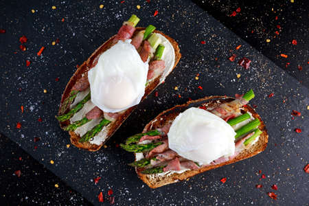 Grilled Toast witch Asparagus, Poached egg, bacon on stone background.の写真素材