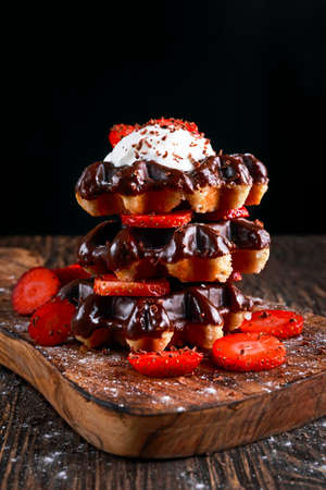Belgian chocolate waffles with fresh strawberry, whipped cream on wooden table.の写真素材