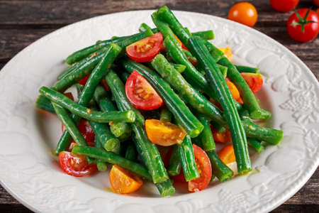 Green beans salad with Red, Yellow Tomatoes on white plateの写真素材