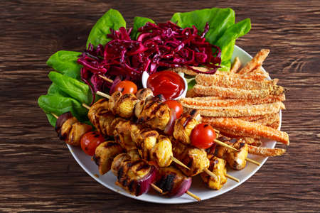 Chicken skewers marinated in turmeric yogurt served with sweet potato and vegetablesの写真素材