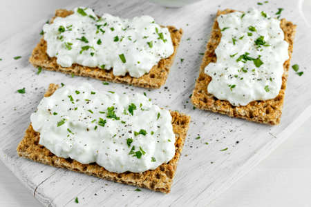 Homemade Crispbread toast with Cottage Cheese and parsley on white wooden board.の写真素材