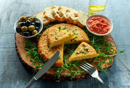 Spanish classic tortilla with potatoes, olives, tomatoes, roccula, bread and herbs.の写真素材