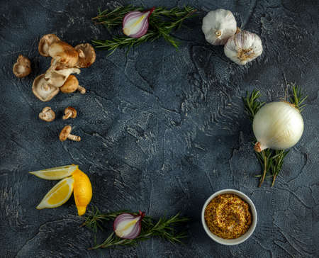 Food preparations for cooking, garlic, onion, wild mushrooms, rosemary, lemon and whole grain mustard on stone tableの写真素材