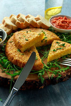 Spanish classic tortilla with potatoes, olives, tomatoes, rucola, bread and herbs.の写真素材