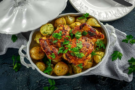 New boiled potatoes with dill and butter served with baked skinless boneless chicken thighs in vintage casseroleの写真素材