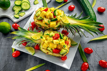 Fresh Juicy Pineapple Cucumber salad with tomatoes, lime on white plateの写真素材