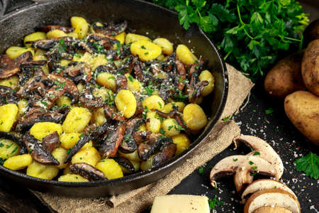 Home made potato gnocchi with mushrooms, chopped parsley and parmesan cheese in iron panの写真素材