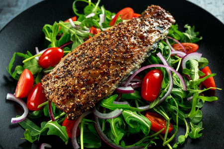 Smoked Mackerel Salad with tomato, chopped red onion, Ruccola on black plate.の写真素材