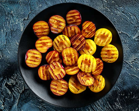 Honey glazed grilled plums on black plate