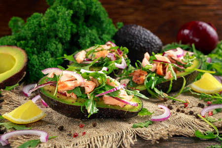 Avocado boats stuffed with salmon, red onion and arugula. concept healthy foodの写真素材