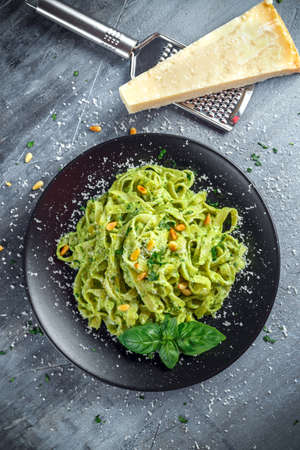 Tagliatelle pasta with pesto sauce, pine nuts and parmesan on black plate.の写真素材