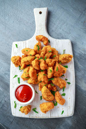 Fried crispy chicken nuggets with ketchup on white board