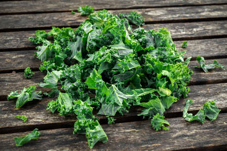 Fresh green healthy superfood vegetable kale leaves on wooden rustic table.の写真素材