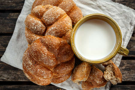 Milk in vintage clay mug and rustic home made bread on linen servietteの写真素材