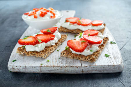 Homemade Crispbread toast with Cottage Cheese and Strawberry on white wooden board.の写真素材