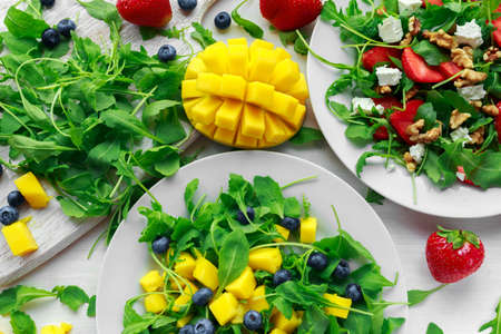 Mango, blueberries salad with arugula on white plateの写真素材