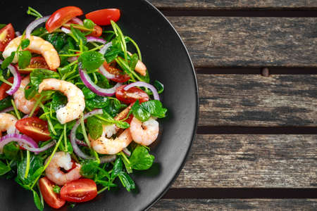 Fresh Healthy Prawns salad with tomatoes, red onion on black plate. concept healthy foodの写真素材