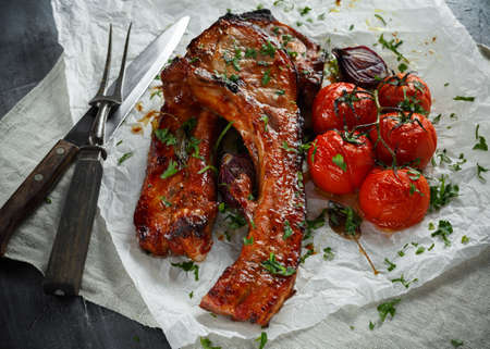 Pork middle chop roast with sweet and sour souce, baked tomatoes and red onionの写真素材