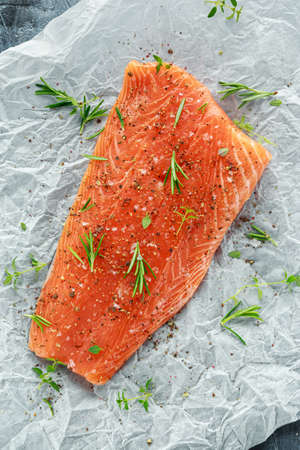 Seasoned Salmon fillet on cooking paper with sea salt, pepper and rosemary. Ready to cookの写真素材