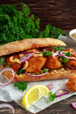 Chicken sandwich with mustard sauce and red onion crumpled paper.の写真素材