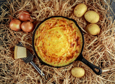 Mashed potato pie baked in rustic pan with onions and parmesan cheese on strawの写真素材