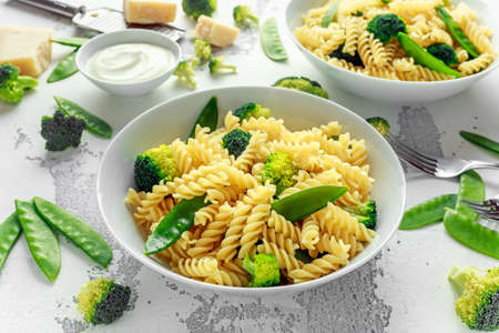 Pasta with green vegetables broccoli, Mange tout and creamy sauce in white plateの写真素材