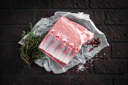 Traditional british raw pork loin joint bone-in with sea salt flakes, pepper and thymeの写真素材
