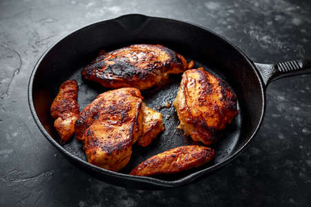 Cooked chicken fillets, breast supremes in rustic cast iron skillet.の写真素材