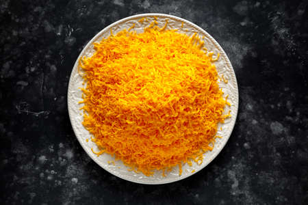 Grated red leicester cheese on plate view from above