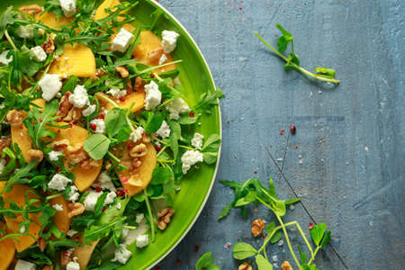 Fresh Tasty Persimmon salad with arugula, nuts, feta cheese, olive oil and herbs. healthy foodの写真素材