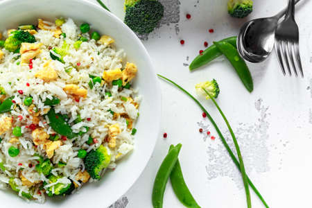 Fried rice with vegetables, broccoli, peas and eggs in a white bowl. soy sauce. healthy foodの写真素材