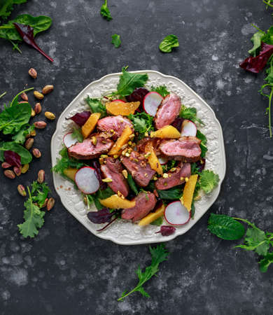 Duck breast fillets steak salad with orange halves, radishes and crushed pistachios
