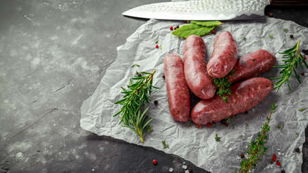 Freshly made raw breed butchers sausages in skins with herbs on crumpled paper.の写真素材