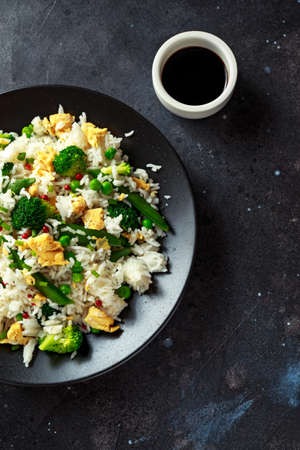 Fried rice with vegetables, broccoli, peas and eggs in a plate. soy sauce. healthy foodの写真素材