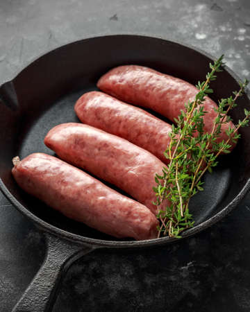 Freshly made raw breed butchers sausages in rustic skillet.の写真素材