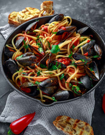 Homemade Pasta Spaghetti with mussels, tomato sauce, chilli and parsley in rustic skillet, pan. sea food mealの写真素材