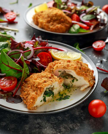 Breaded Chicken Kiev breast stuffed with butter, garlic and herbs served with vegetables in a plate.の写真素材