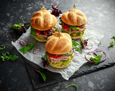 Fresh home sandwich with avocado guacamole, tomatoes, arugula, red onion and ham.の写真素材