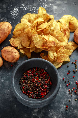cooked creamy peppercorn potato chips, snack crisps with sea salt on stone board with marble pestle and mortar.の写真素材