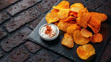 Potato chips, snack crisps with red paprika and white dip sauceの写真素材